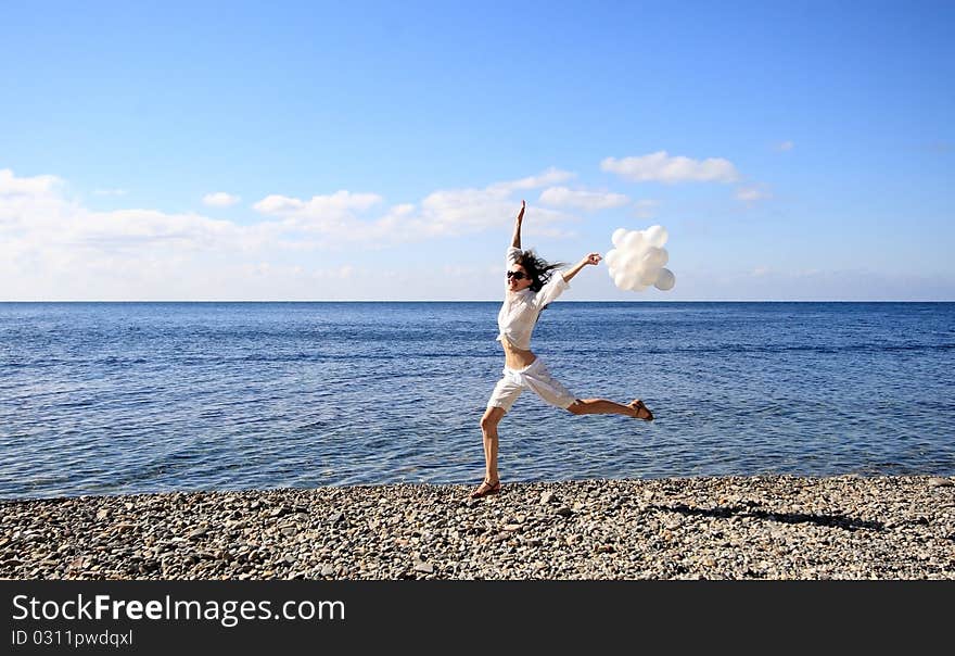 Happy young woman with white balloons on the seashore. Happy young woman with white balloons on the seashore