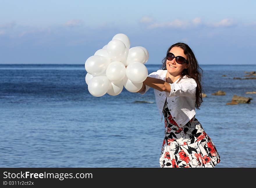 Happy young woman with white balloons on the seashore. Happy young woman with white balloons on the seashore