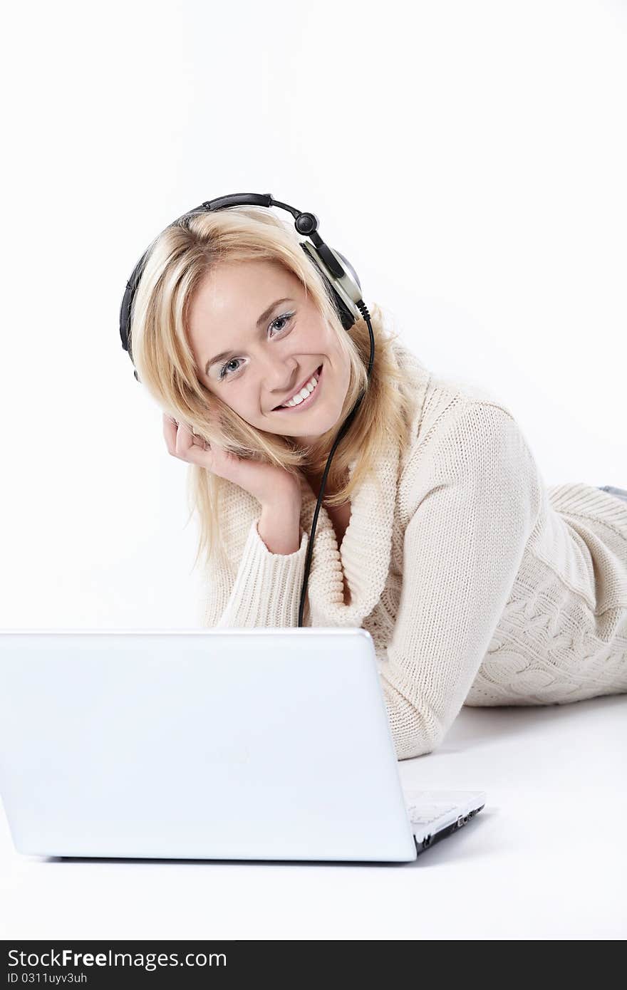 Young beautiful girl in headphones with a laptop on a white background