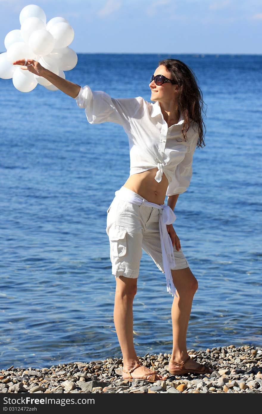 Happy young woman with white balloons on the seashore. Happy young woman with white balloons on the seashore