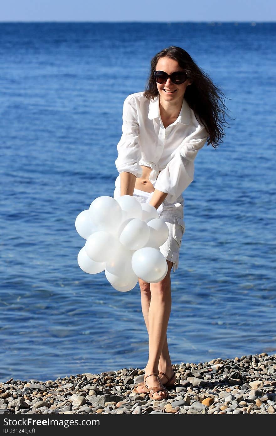 Happy young woman with white balloons on the seashore. Happy young woman with white balloons on the seashore