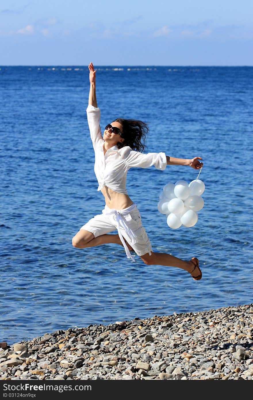 Happy young woman with white balloons on the seashore. Happy young woman with white balloons on the seashore