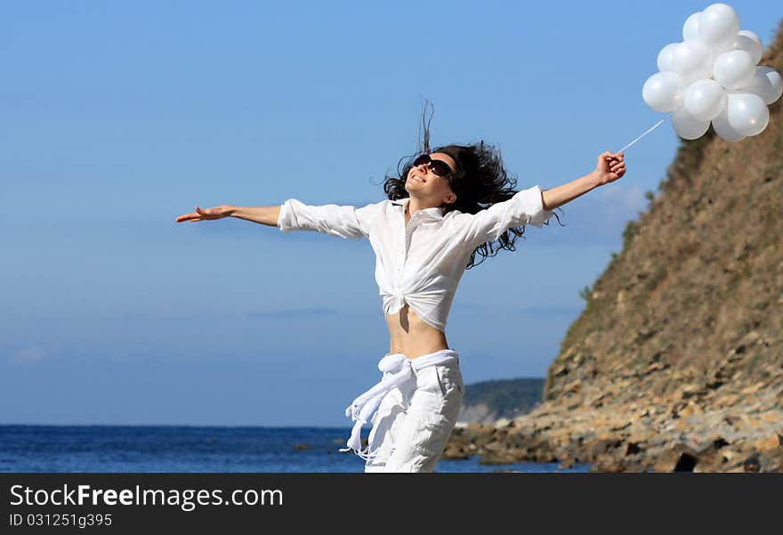 Happy young woman with white balloons on the seashore. Happy young woman with white balloons on the seashore