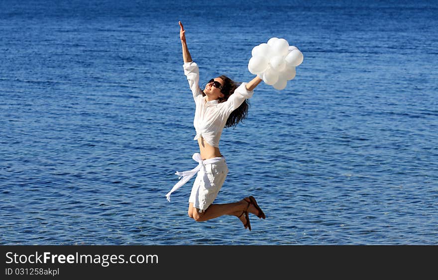 Happy young woman with white balloons on the seashore. Happy young woman with white balloons on the seashore