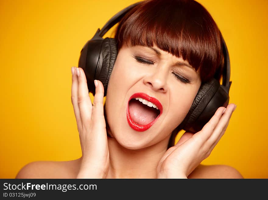 Portrait of a beautiful woman with headphones isolated on yellow