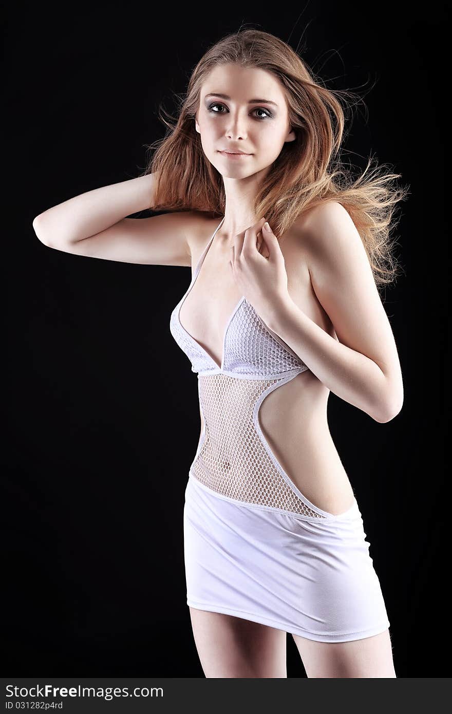 Shot of an attractive young woman in white dress posing over black background. Shot of an attractive young woman in white dress posing over black background.