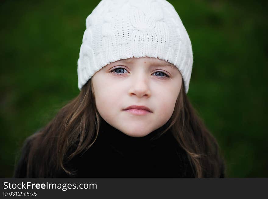 Beauty small girl with blue eyes and dark long hair in white knit hat. Beauty small girl with blue eyes and dark long hair in white knit hat