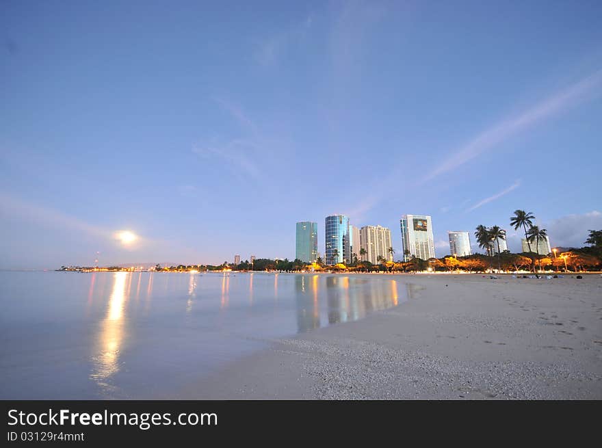 Moon Set Over The Ocean With Buildings