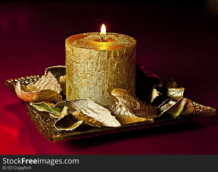 Richly decorated Christmas candle on the golden dish of golden petals ornament. Richly decorated Christmas candle on the golden dish of golden petals ornament.