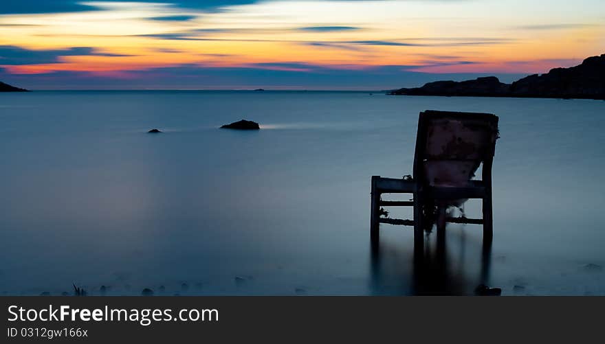 An old chair sitting in water on swedish coast. An old chair sitting in water on swedish coast