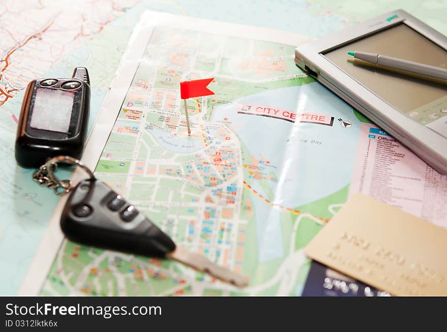 Road map with a red flag, car keys, electronic organizer and credit cards. closeup. Road map with a red flag, car keys, electronic organizer and credit cards. closeup.