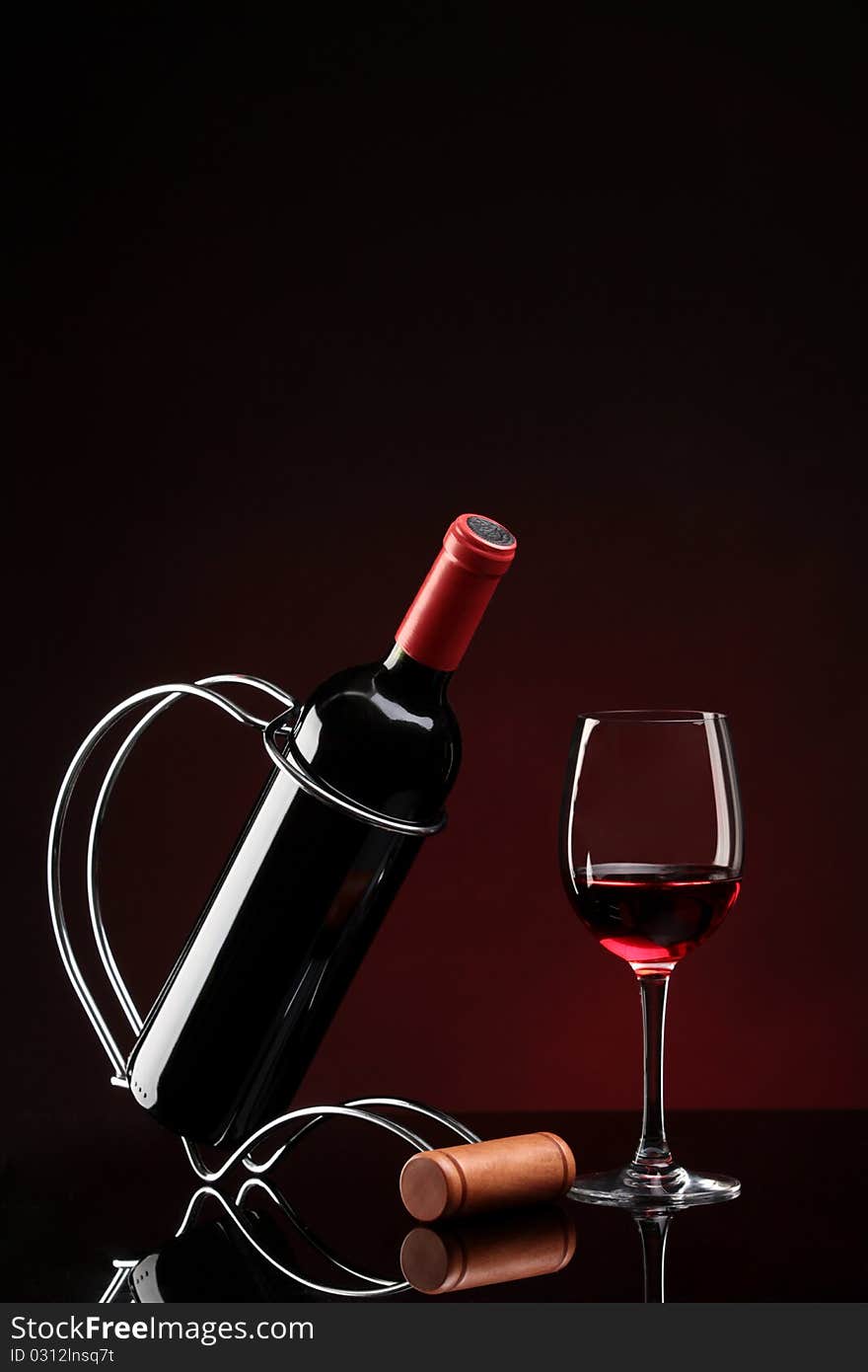 Bottle with red wine on a stand and glass