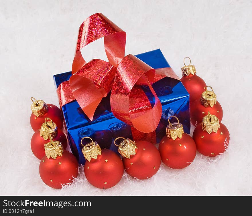 Red spheres and blue box with red bow on the white fur