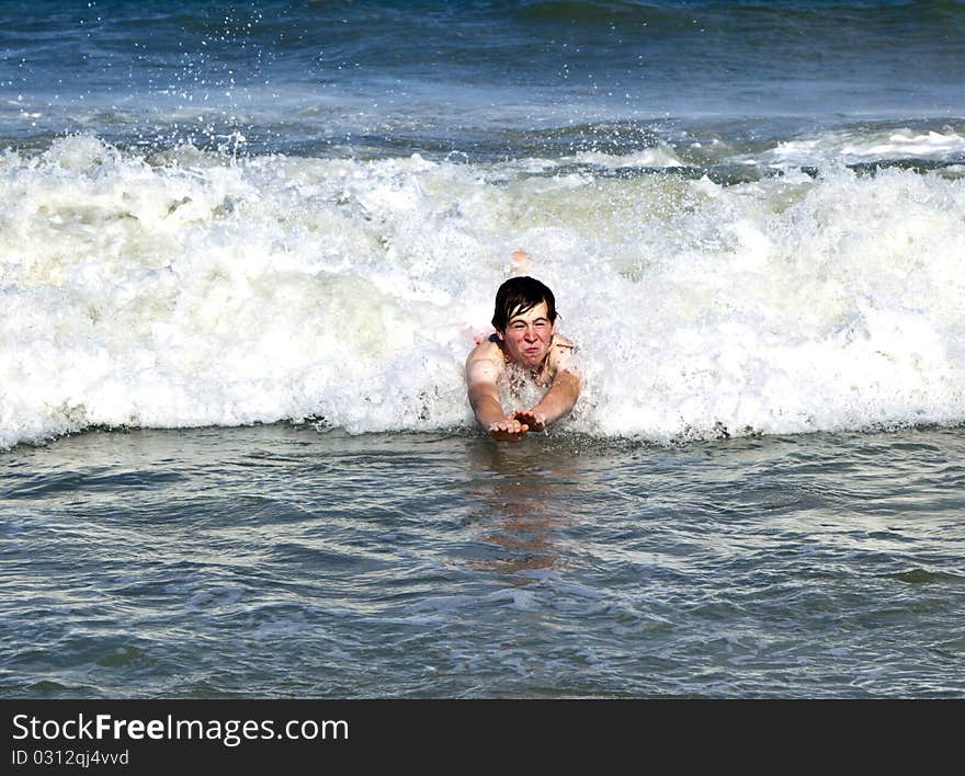 Young boy is body surfing in the waves