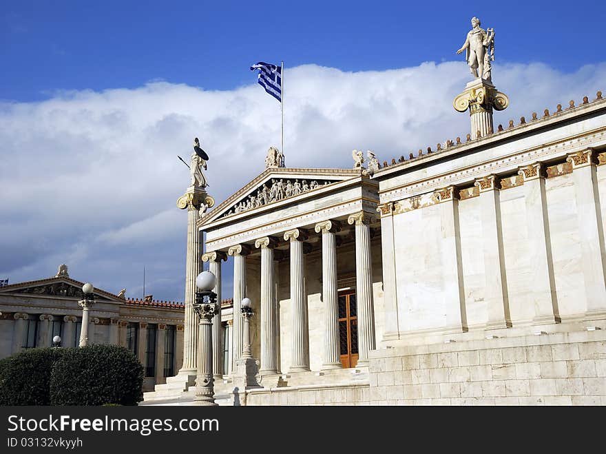 The National Academy Building in Athens. The building, which was built from 1859-1885, is located on the south of The University of Athens' main building (Panepistimio street). In front of the facade stand two high ionic columns, which bear the colossal statues of Athena (Minerva) and Apollo. The National Academy Building in Athens. The building, which was built from 1859-1885, is located on the south of The University of Athens' main building (Panepistimio street). In front of the facade stand two high ionic columns, which bear the colossal statues of Athena (Minerva) and Apollo.