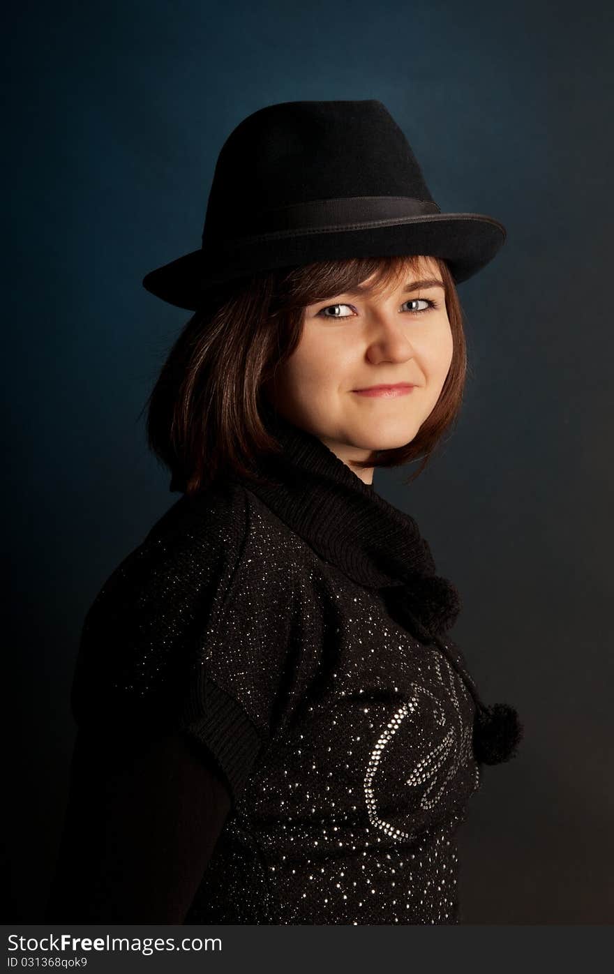 Portrait of attractive young girl in hat. Against a dark background