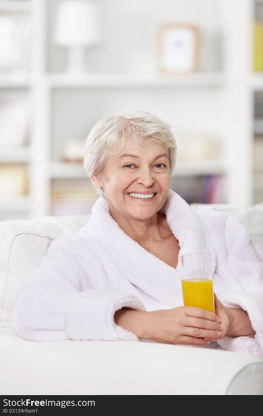 Smiling attractive woman in a bathrobe with a glass of juice. Smiling attractive woman in a bathrobe with a glass of juice