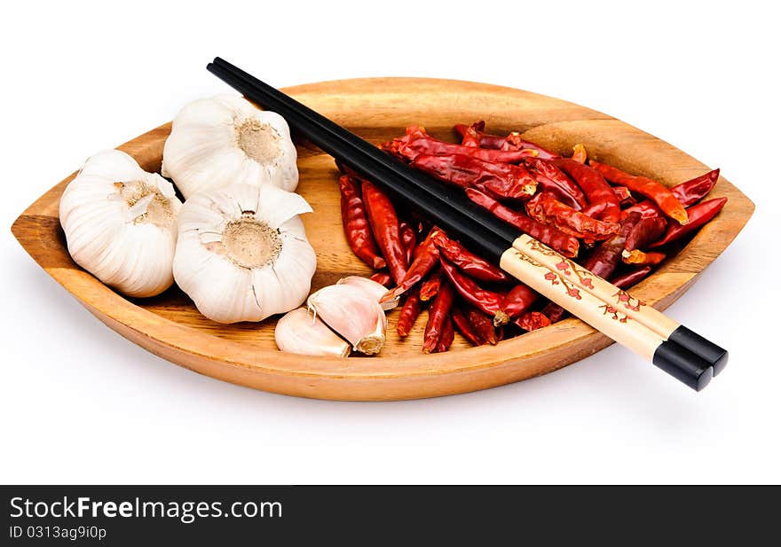 Chop sticks, chili fruit and some garlic on a wooden plate. Chop sticks, chili fruit and some garlic on a wooden plate