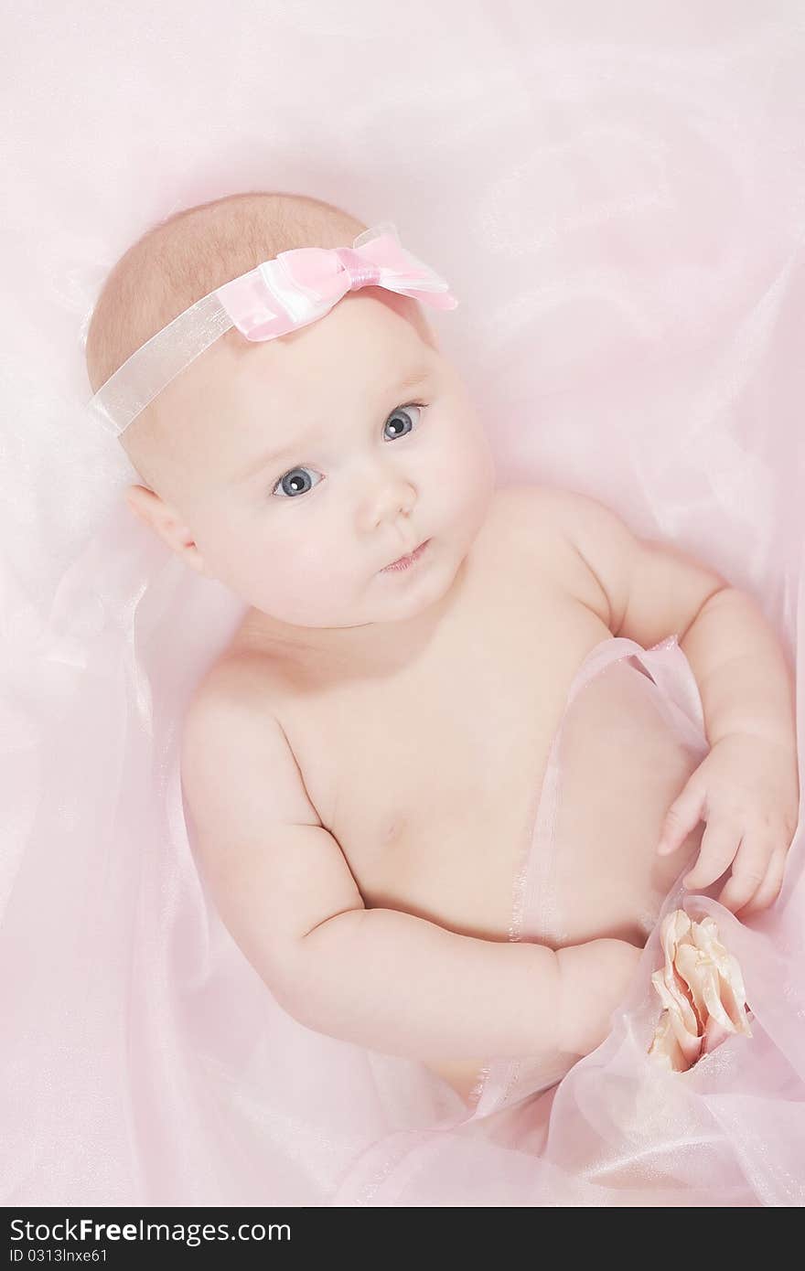 Portrait of a little baby on a soft blanket with a pink bow