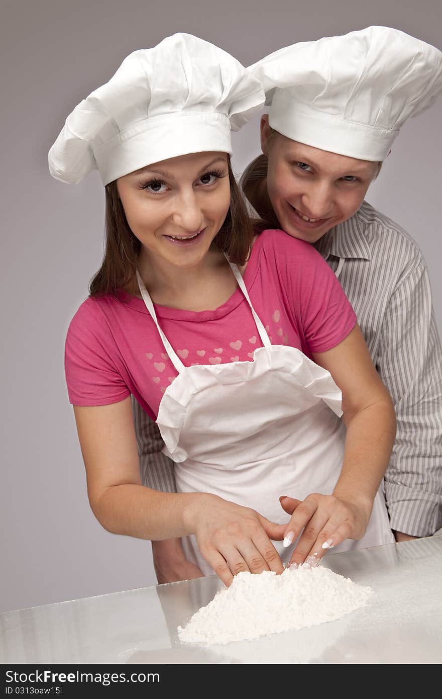 Young loving couple playing with dough. Over white background