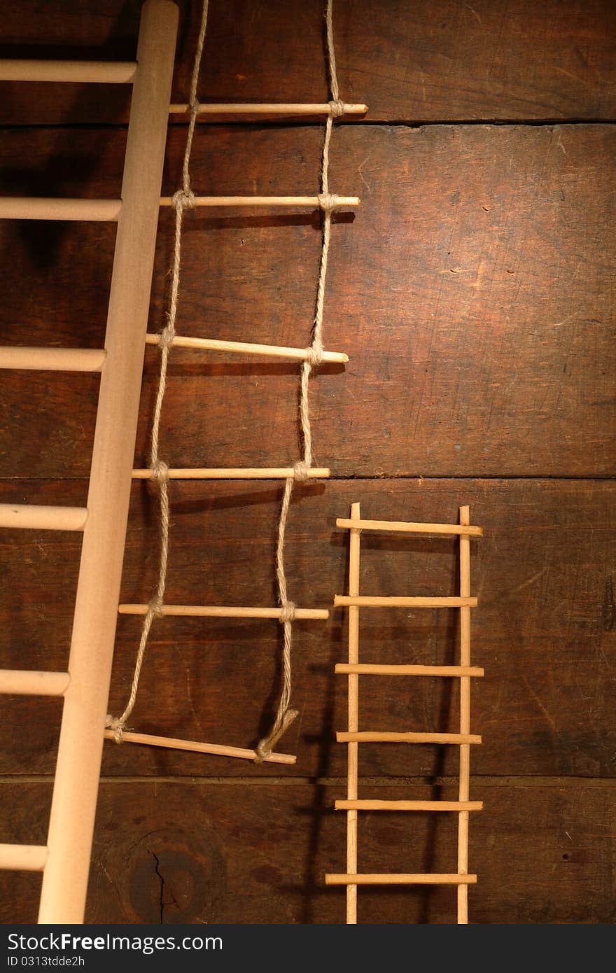 Three various ladders on old brown wooden background. Three various ladders on old brown wooden background