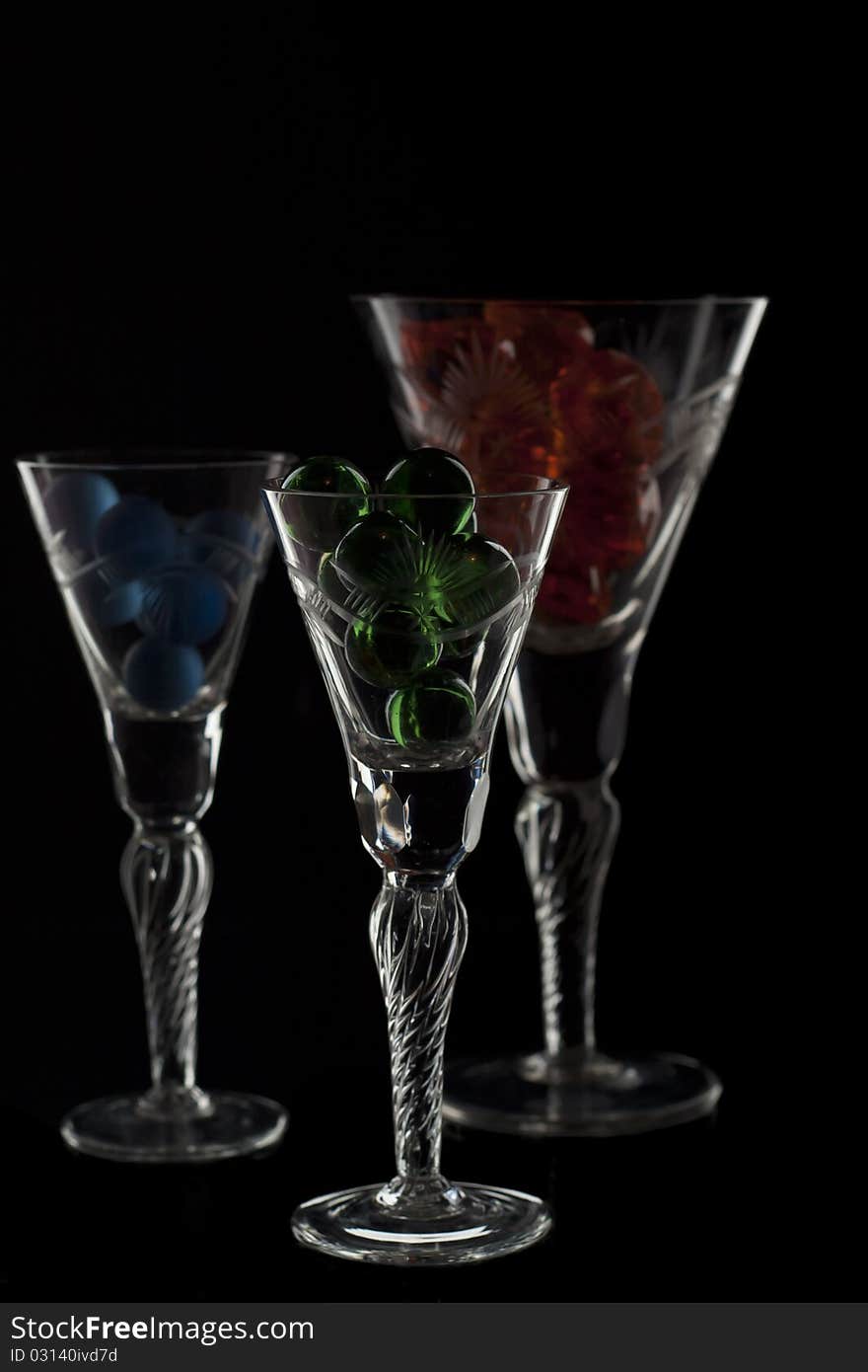 Different glasses full with marbles isolated on black