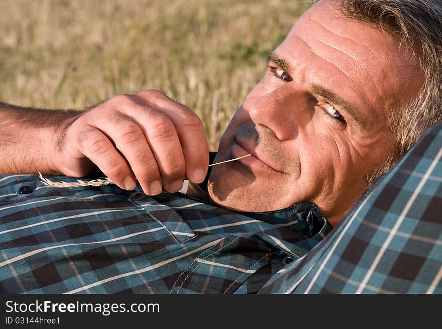 Happy smiling mature man lying down on a meadow and relaxing. Happy smiling mature man lying down on a meadow and relaxing