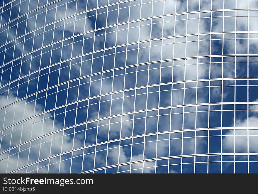 Reflection of a cloudy sky in glass wall of an office building