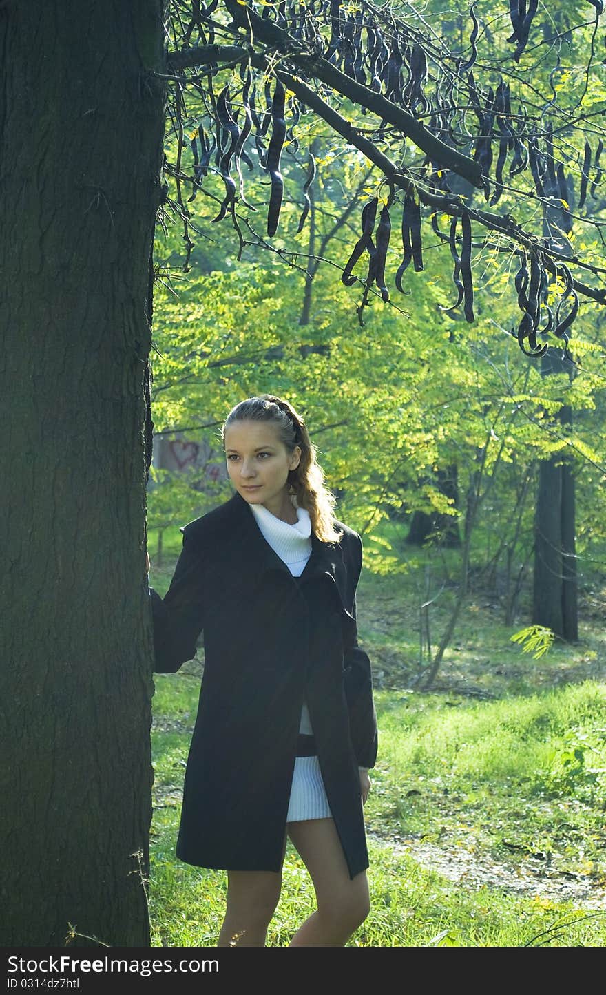 Girl stayning under the dark mysterious tree in the park