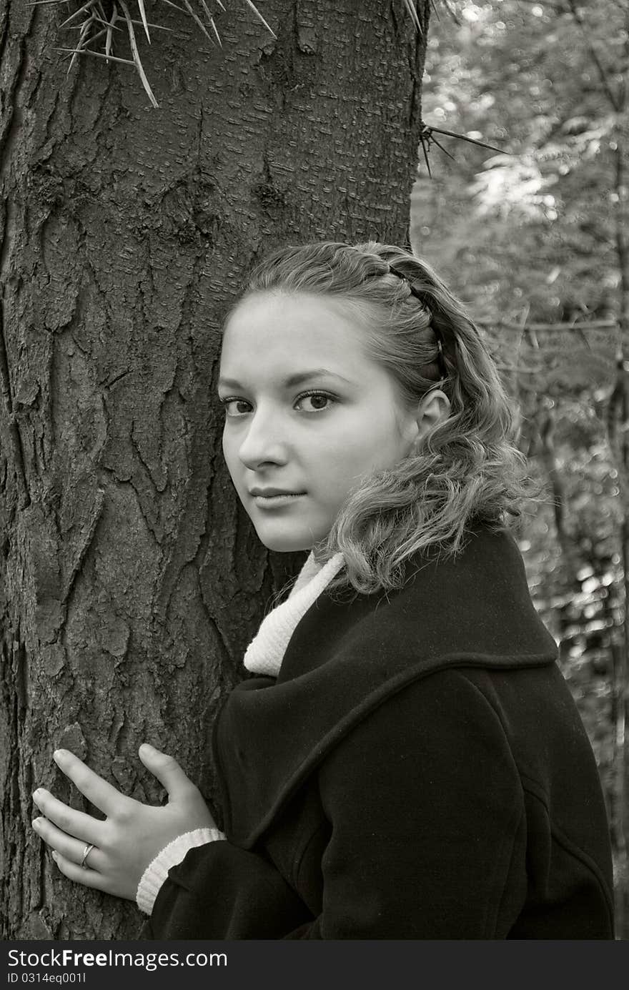 Tender girl near a dark tree trunk. Black and white