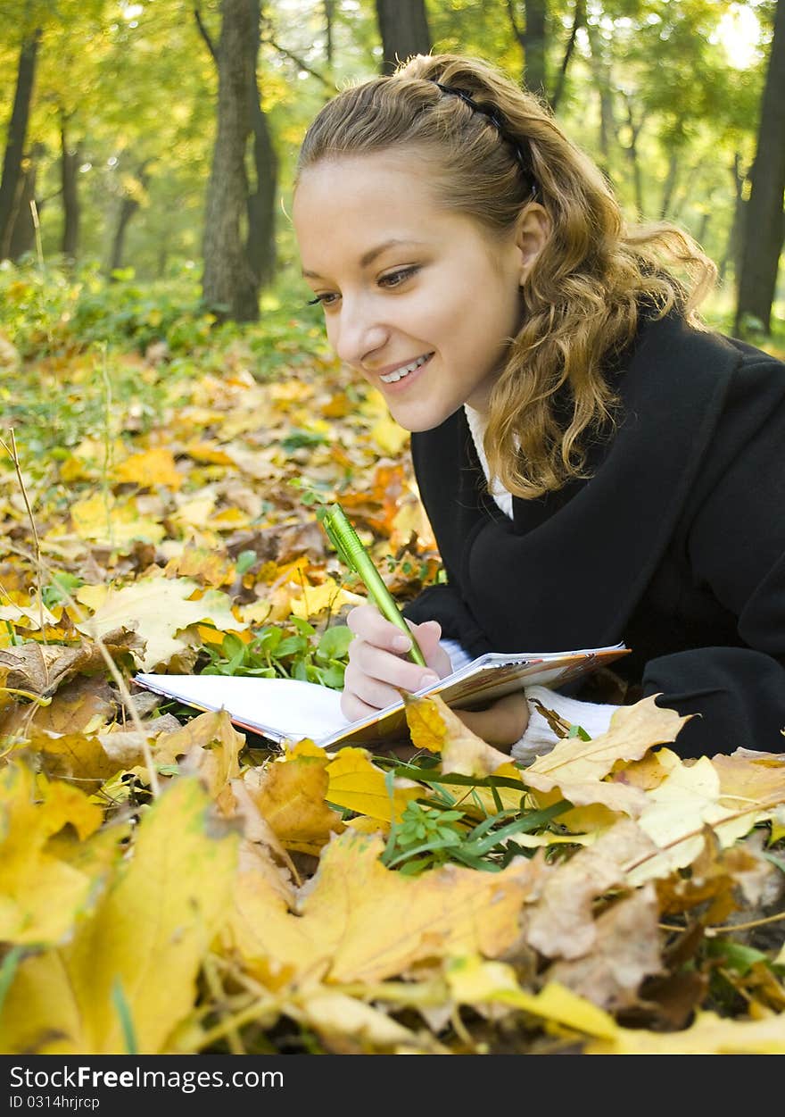 Happy teen girl lies in the park with her diary and laughs