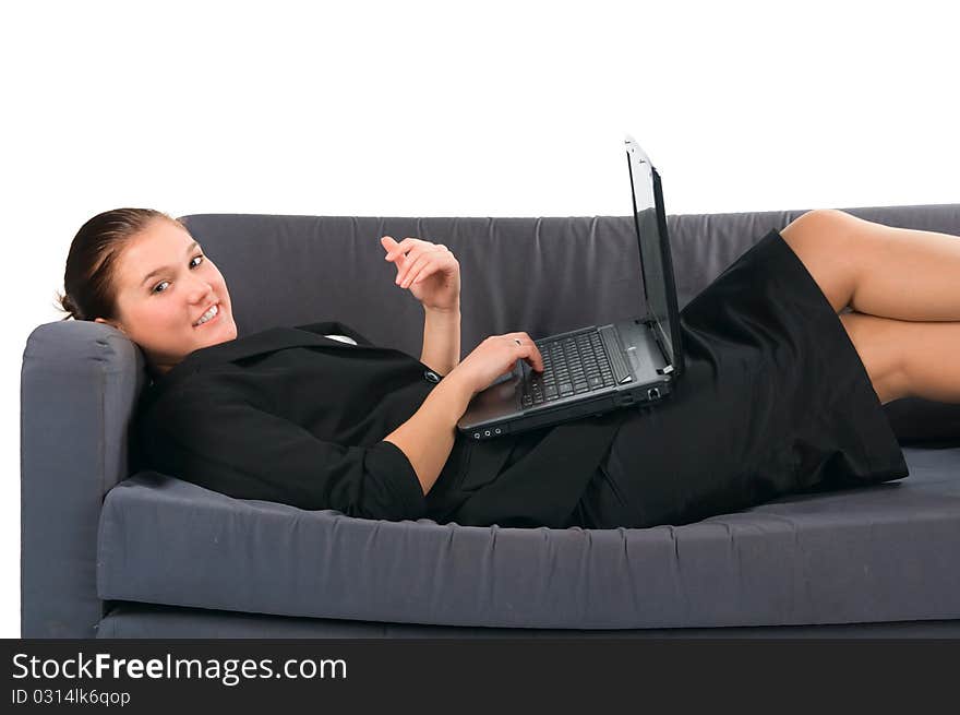 The beautiful businesswoman works at the computer, lying on a sofa