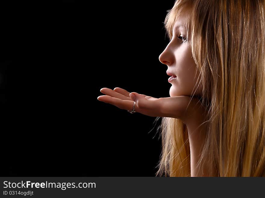 Glamour blonde woman with hand on black background