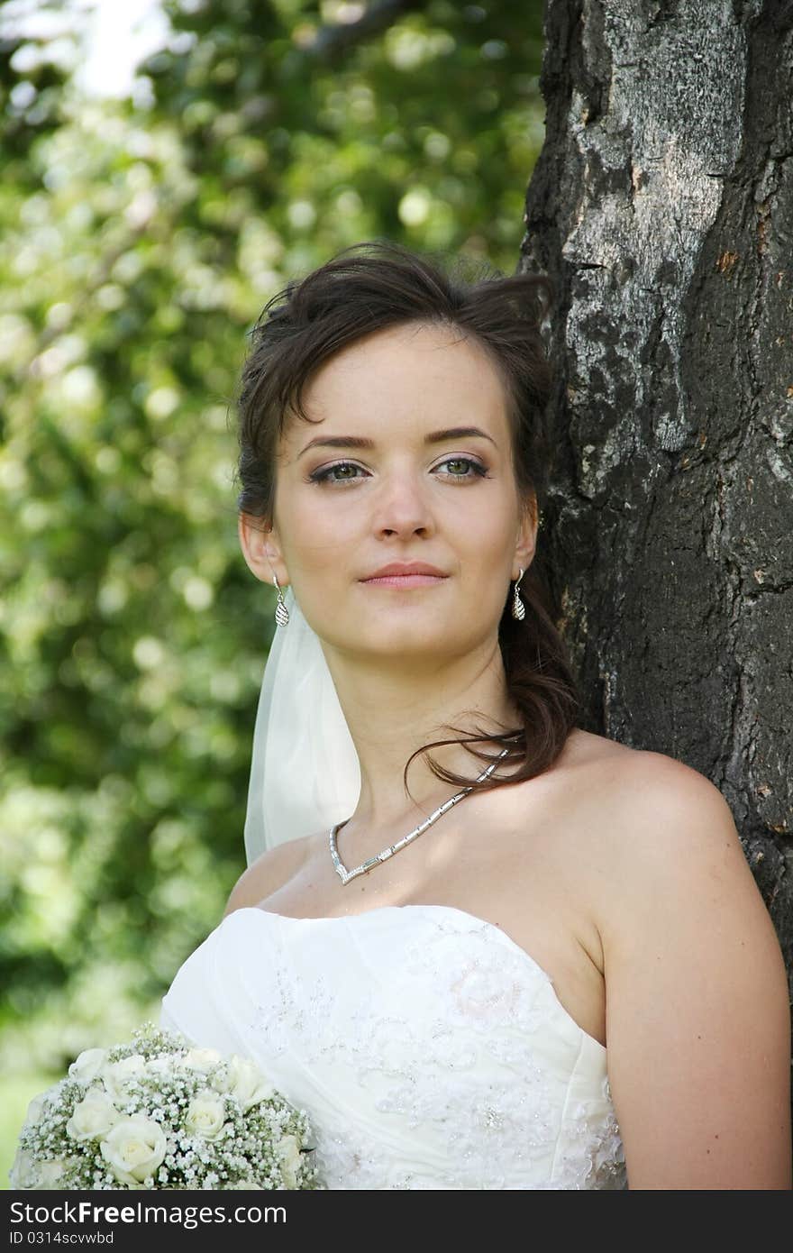 Portrait of Ukrainian fiancee with a wedding bouquet in hands, stands under a birch