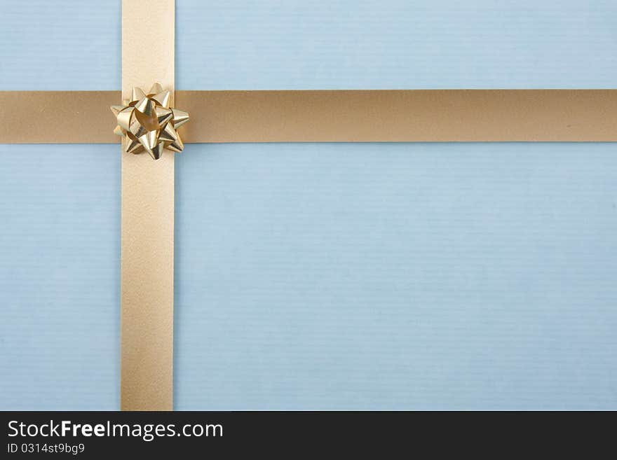 Christmas back ground with gold ribbon on light blue paper and a small rosette. Christmas back ground with gold ribbon on light blue paper and a small rosette