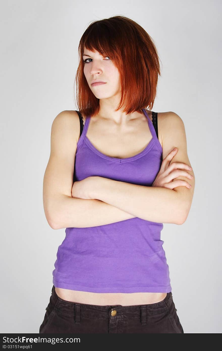 Young redhead girl in purple shirt with crossed hands, dissatisfaction emotion, half body. Young redhead girl in purple shirt with crossed hands, dissatisfaction emotion, half body