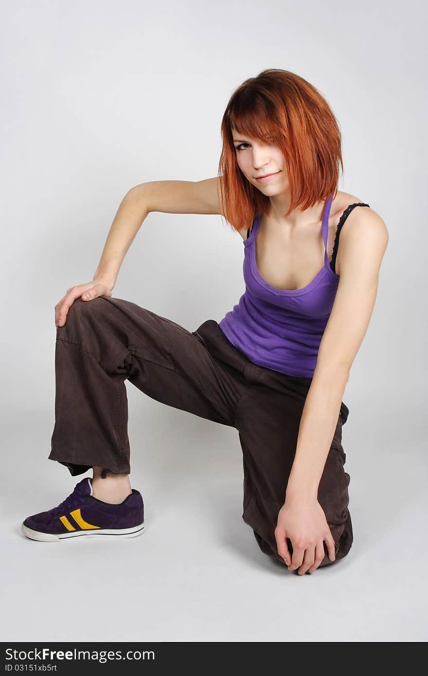 Redhead girl in hip-hop clothes sitting