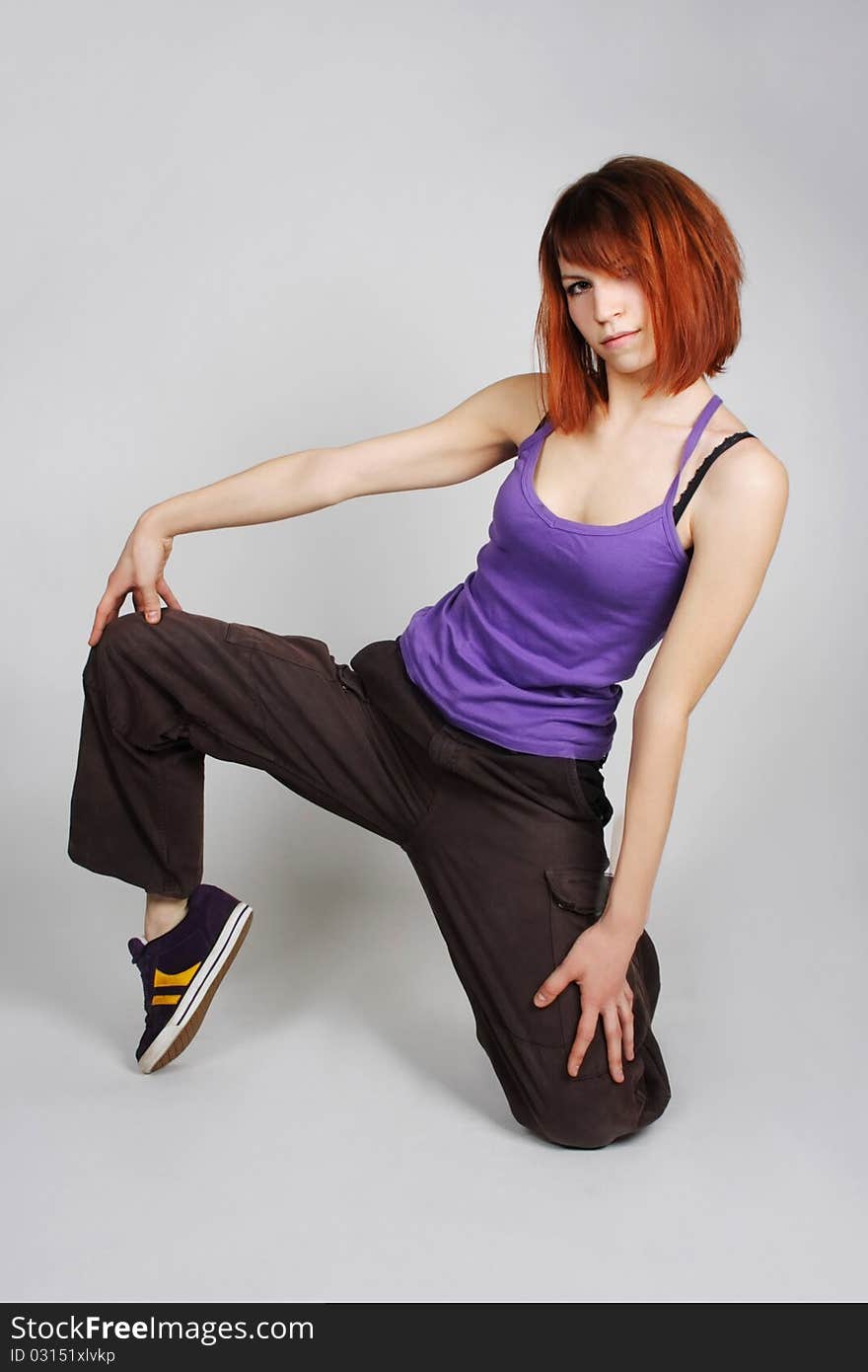 Young redhead girl in hip-hop clothes sitting