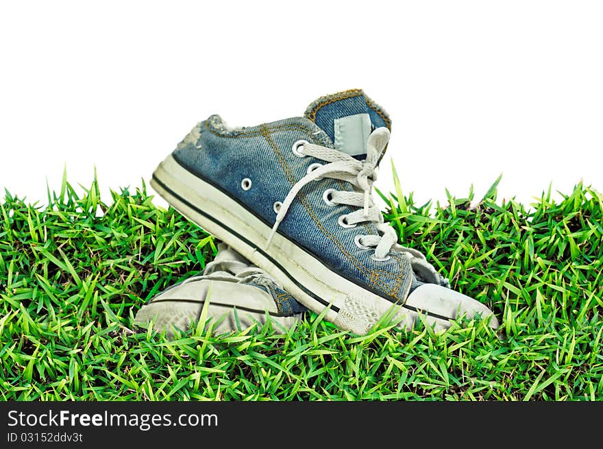 Old, dirty sneakers over spring green grass,white background ,isolated