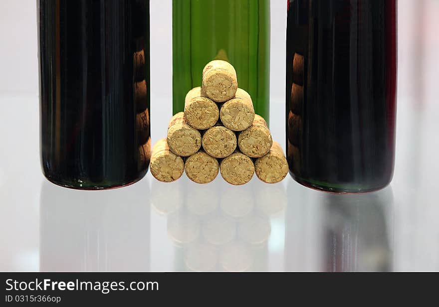 Bottles with wine and wine stoppers on a glass surface