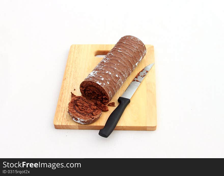 A yule log on a wooden chopping board with a chopped slice