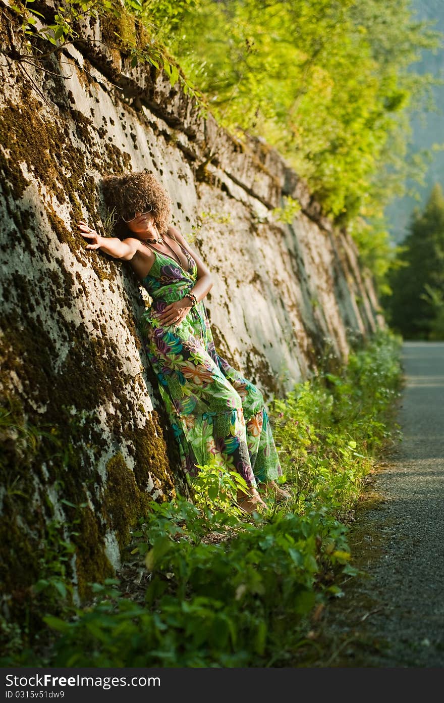 Beatiful girl near wall against the backdrop of lush nature