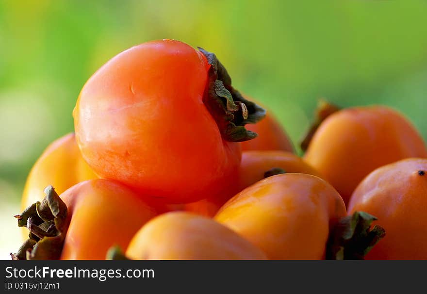 Mature caqui fruits on green background. Mature caqui fruits on green background.