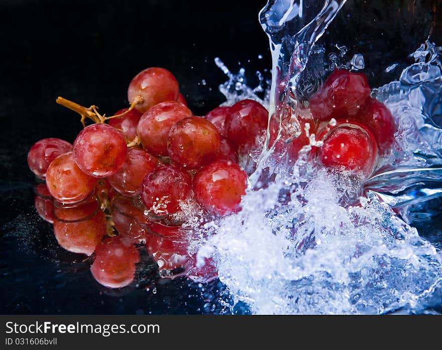 Grapes and splash water over black background