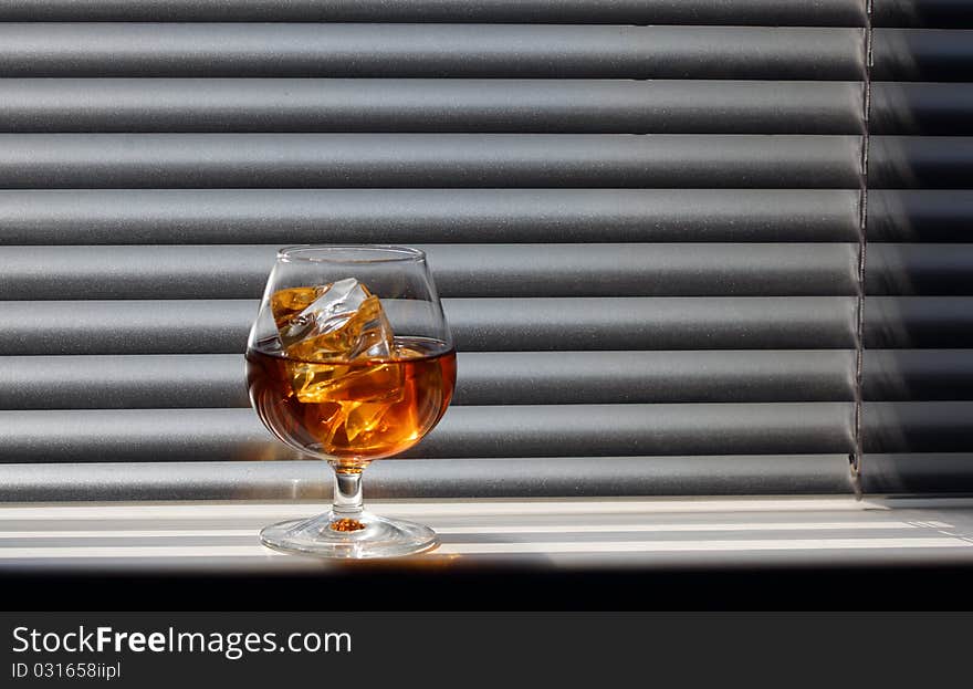 Whisky glass with ice on a window sill