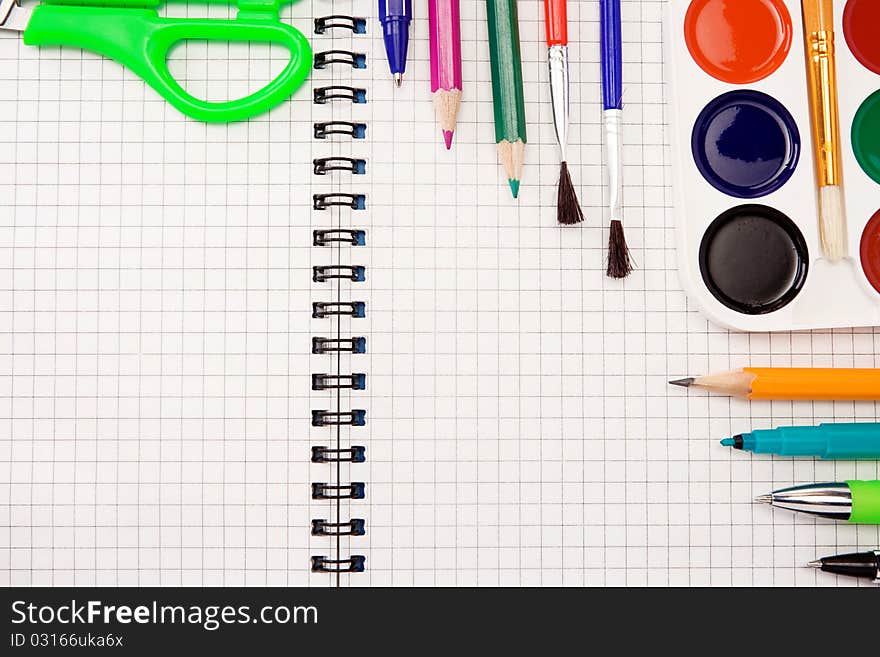 Pencils, felt pens, paint brush and scissors on checked paper of notebook. Pencils, felt pens, paint brush and scissors on checked paper of notebook