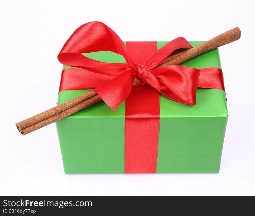 Gift in green wrapping with a red bow decorated with cinnamon stick on white background. Gift in green wrapping with a red bow decorated with cinnamon stick on white background