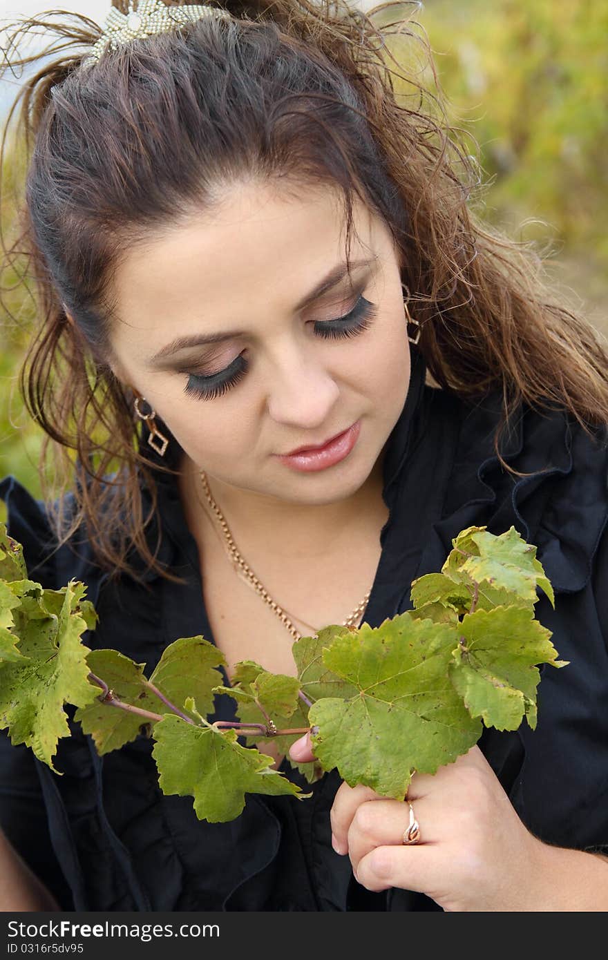 Portrait of attractive lady with great make-up, closed her eyes with vine sprout. Portrait of attractive lady with great make-up, closed her eyes with vine sprout