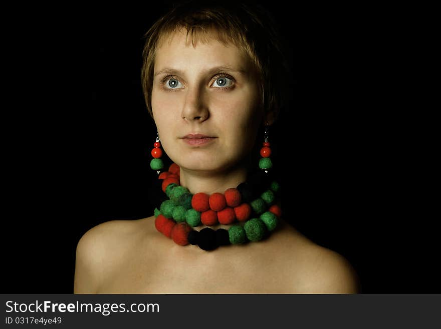 Young woman with bare shoulders in her wearing a necklace and earrings made of wool. Ethnos. Young woman with bare shoulders in her wearing a necklace and earrings made of wool. Ethnos