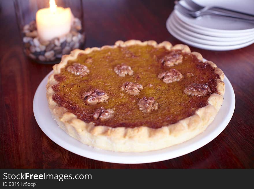 Pumpkin pie with walnuts on a plate with a candle.